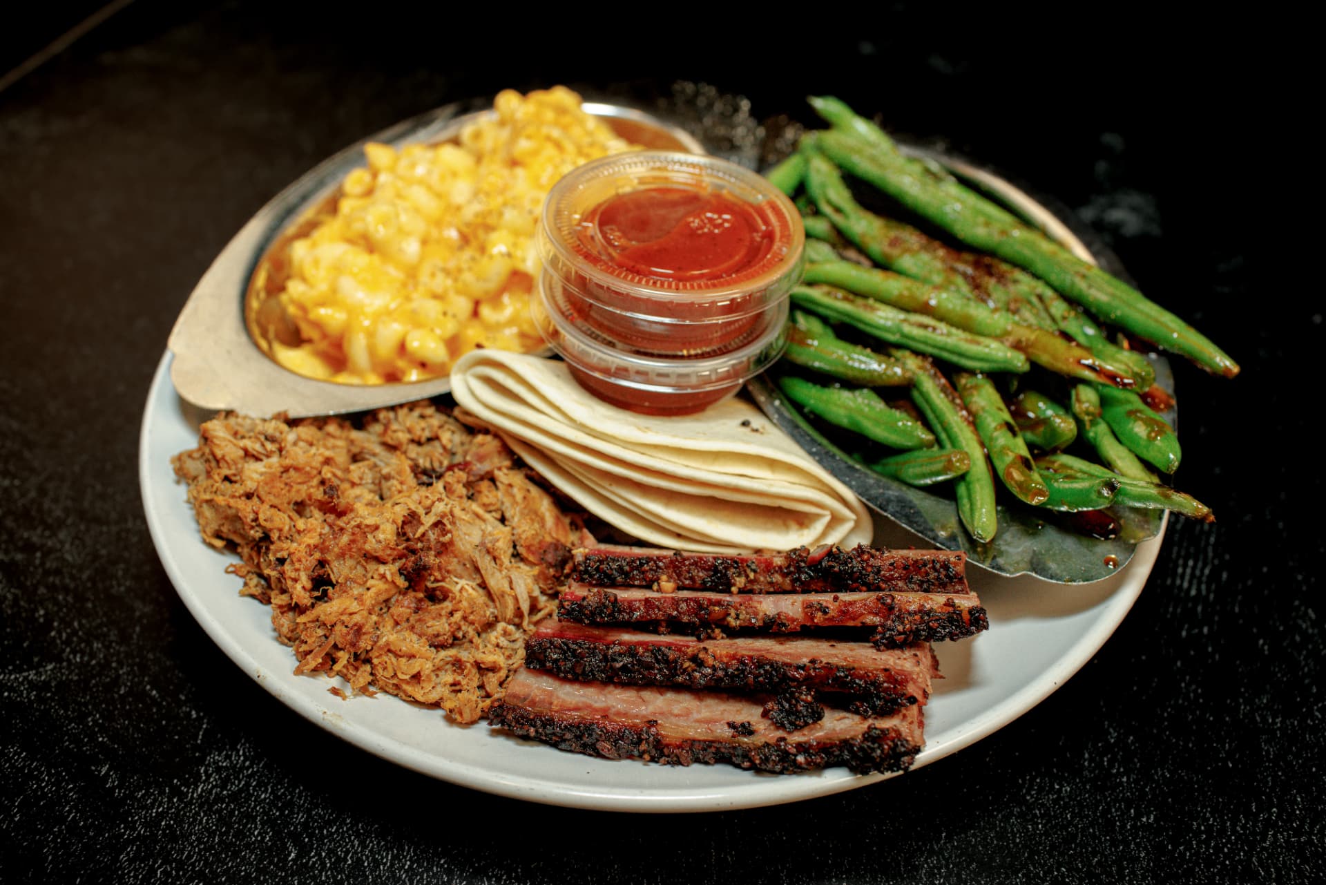 Smoked brisket and pulled pork plate with mac and cheese, green beans and BBQ sauce